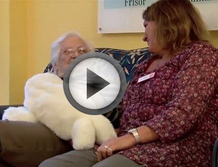 Eine demenzkranke Seniorin kuschelt mit der computergesteuerten Kuschelrobbe Paro.