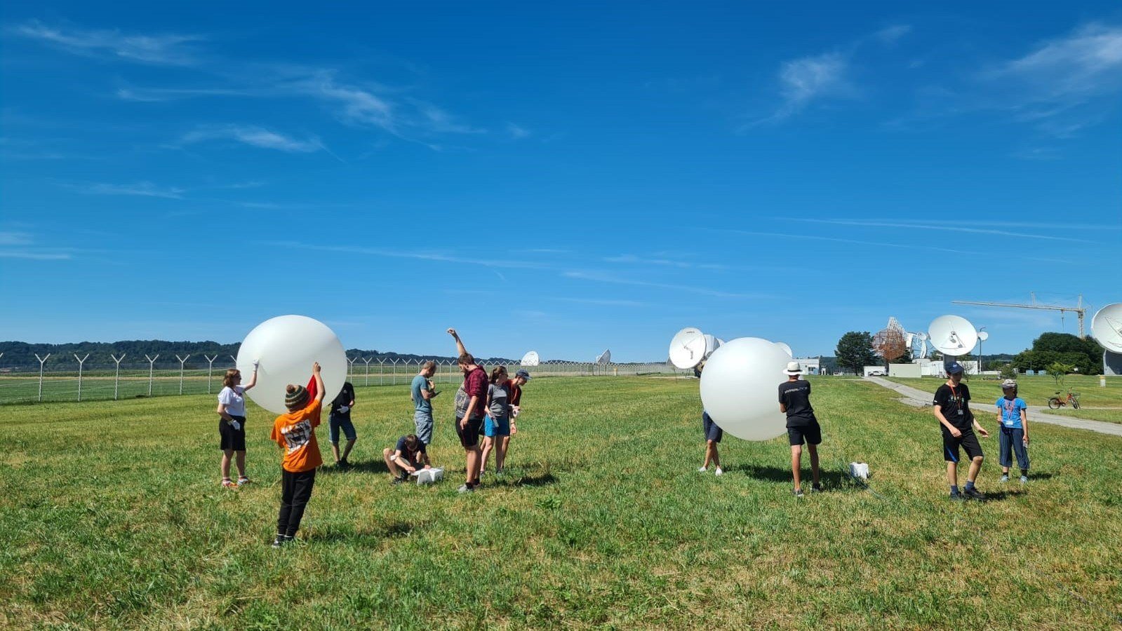 Eine Gruppe Schülerinnen und Schüler mit Ballons auf einer Wiese.