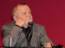 Dr. Rüdiger Safranski sitzt mit einem Arm seinen Kopf stützend an einem Konferenztisch und blickt zu einem Gesprächspartner, der nicht im Bild ist.