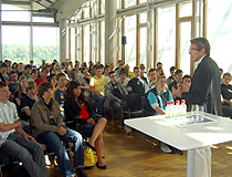 Ein Mann hält eine Rede vor vielen sitzenden Jugendlichen.