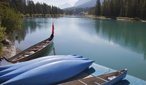 Das Bild zeigt eine kanadische Flusslandschaft. Kanuboote sind an einem Bootssteg befestigt