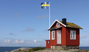 Rotes Häuschen mit schwedischer Flagge an der schwedischen Küste
