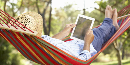 Rentner in der Hängematte mit Tablet-PC