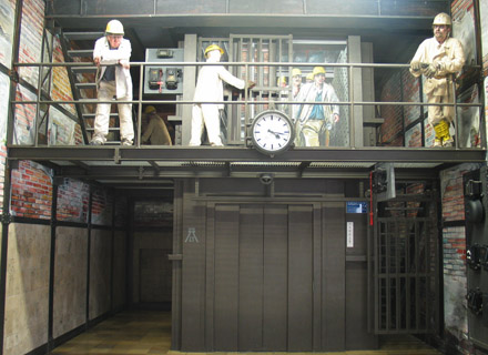 In einer Schachthalle steigen mehrere Arbeiter aus einem Fahrstuhl.