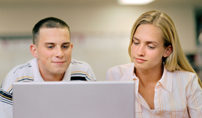 Eine Frau und ein Mann sitzen vor einem Laptop