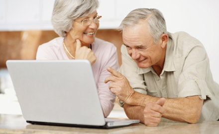 Zwei Senioren unterhalten sich vor einem Laptop