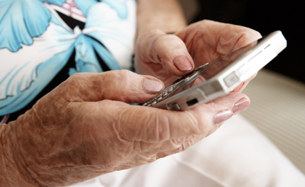 Eine ältere Frau bedient ein Smartphone.