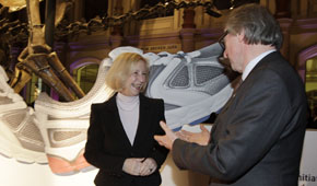 Bildungsministerin Johanna Wanka diskutiert mit einem Gast der Eröffnungsveranstaltung. Im Hintergrund ist ein Dinosaurierskelett zu sehen.