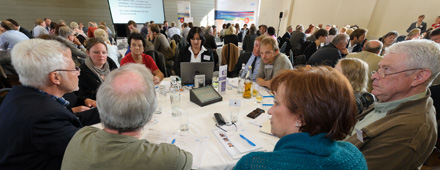 Teilnehmer einer regionalen Bürgerkonferenzen sitzen an einem Tisch und diskutieren