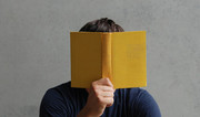 Eine Person hält ein Buch vor ihr Gesicht