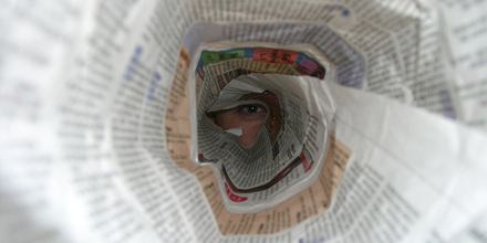 Ein Auge blickt durch eine Zeitungsrolle