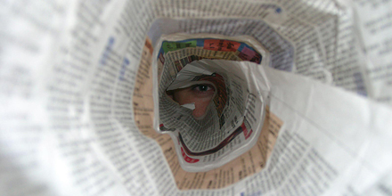 Ein Auge blickt durch eine Zeitungsrolle