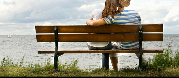 Zwei Personen sitzen auf einer Bank und umarmen sich.