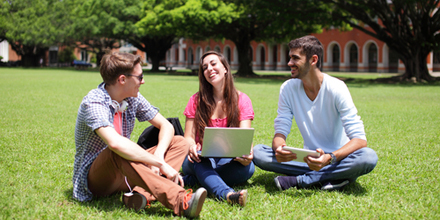 Drei Jugendliche sitzen auf der Wiese und unterhalten sich.