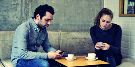 Zwei Menschen im Café sind mit ihren Smartphones beschäftigt