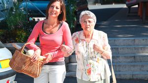 Frau hilft älterer Dame über Straße