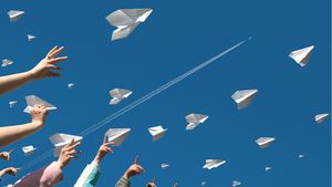 Menschen werfen Papierflieger