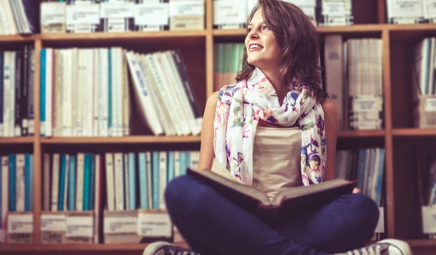 Junge Frau sitzt vor Bücherregal