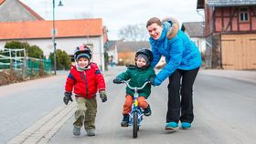 Mutter bringt ihren zwei Kindern Radfahren bei