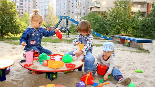 Spielende Kinder im Sandkasten vor Hochhäusern