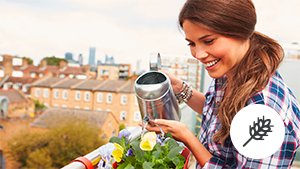 Frau gießt auf einem Balkon Blumen