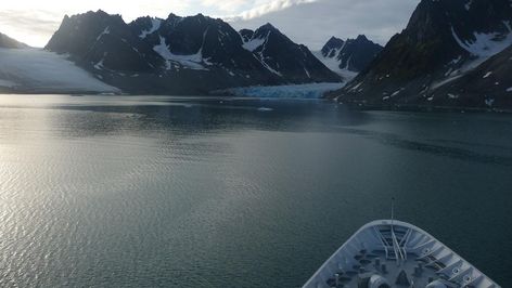 Der Bug eines Schiffes vor der Kulisse eines ins Meerwasser reichenden Gletschers
