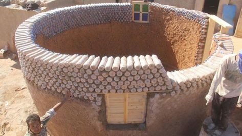 Foto einer kreisrunde, weiß gestrichenen Hütte, die aus mit Sand gefüllten Plastikflaschen gebaut wurde.