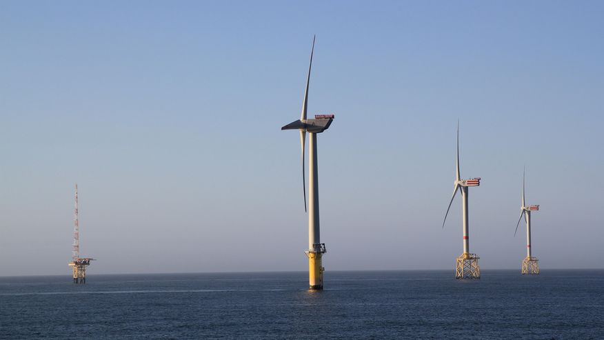 Foto, das einen Windpark und eine Forschungsplattform im Meer zeigt. So wird Energie aus dem Wind auf dem Meer gewonnen.
