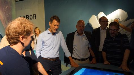 Foto, auf dem Dr. Georg Schütte, Staatssekretär im Bundesministerium für Bildung und Forschung, und andere Personen in der Ausstellung des Ausstellungsschiffes MS Wissenschaft zu sehen sind