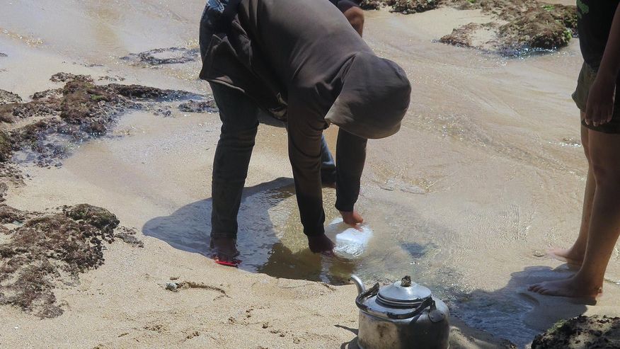 Foto Indonesiers der Trinkwasser aus einer Quelle am Strand in Südjava schöpft