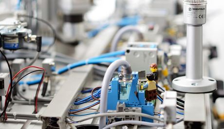 Zwei Legofiguren stehen auf einem Schaltkreis einer Produktionsanalge und verdeutlichen symbolhaft das Ziel hinter der "fortiss future factory". Eine sich der produktionsanforderung selbständig anpassende Produktionsanlage 