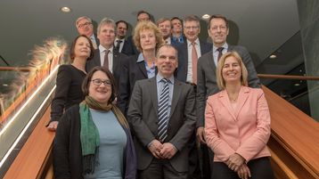 Auf einer Treppe aufgereiht, stehen die Mitglieder des Lekungskreis der Plattform Lernende Systeme.