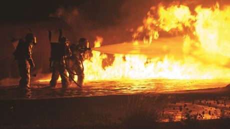 Feuerwehrkräfte bekämpfen eine große Flammenwand mit Löschwasser. Die Einsätze der Feuerwehr sind sehr gefährlich. Deswegen wird nach technischen Lösungen geuscht um diese Gefahren zu reduzieren.
