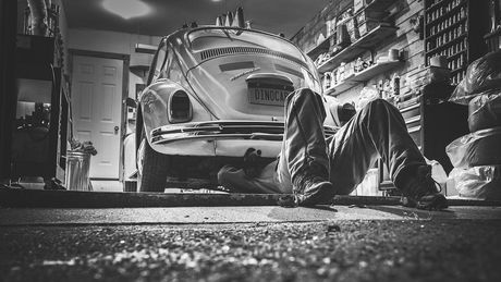 In einer Garage steht ein VW Käfer darunter liegt ein Mensch un repariert das Auto. Ein Symbolphoto, für den millionsten verkauften VW Käfer am 05. August 1955