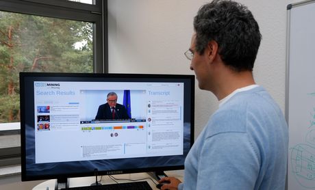 Mann steht am Monitor und testet Audio-Mining-System des Fraunhofer IAIS.