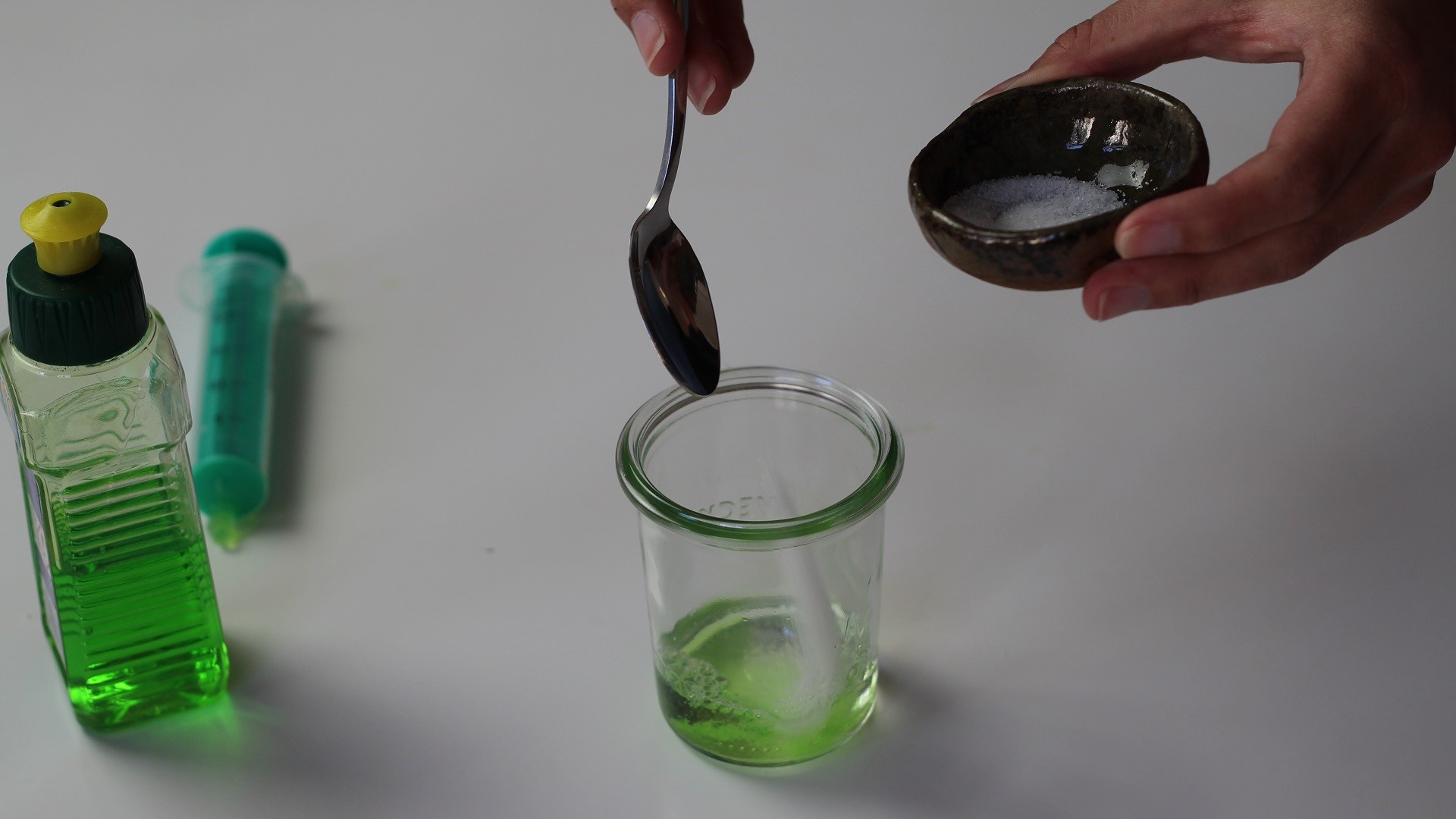Eine Person gibt mit einem Teelöffel Fruchtmus in ein Glas.