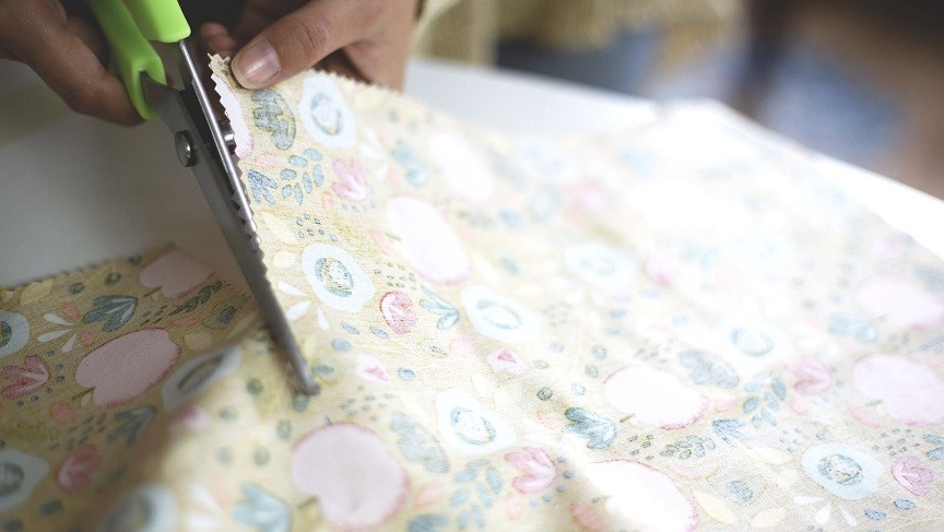 Ein Baumwolltuch wird mit einer Schere zugeschnitten
