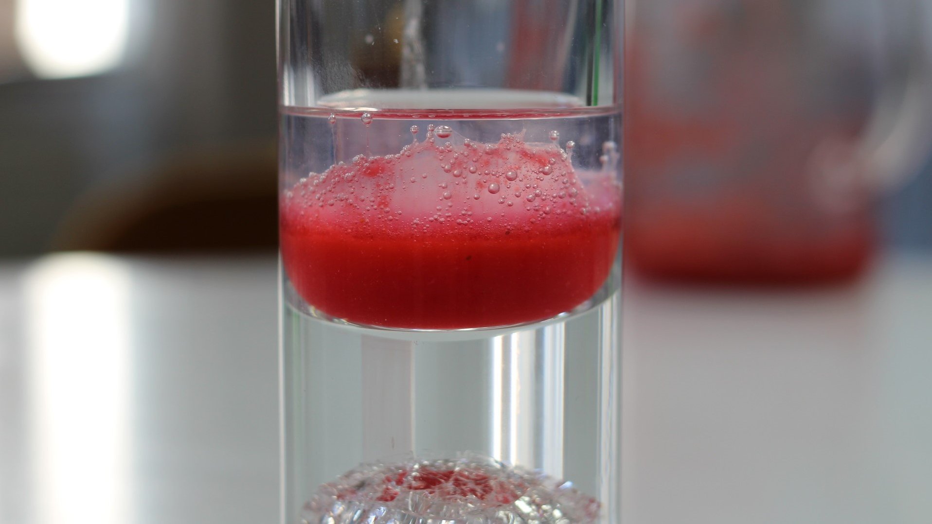 Glas mit einer roten, filtrierten Lösung.