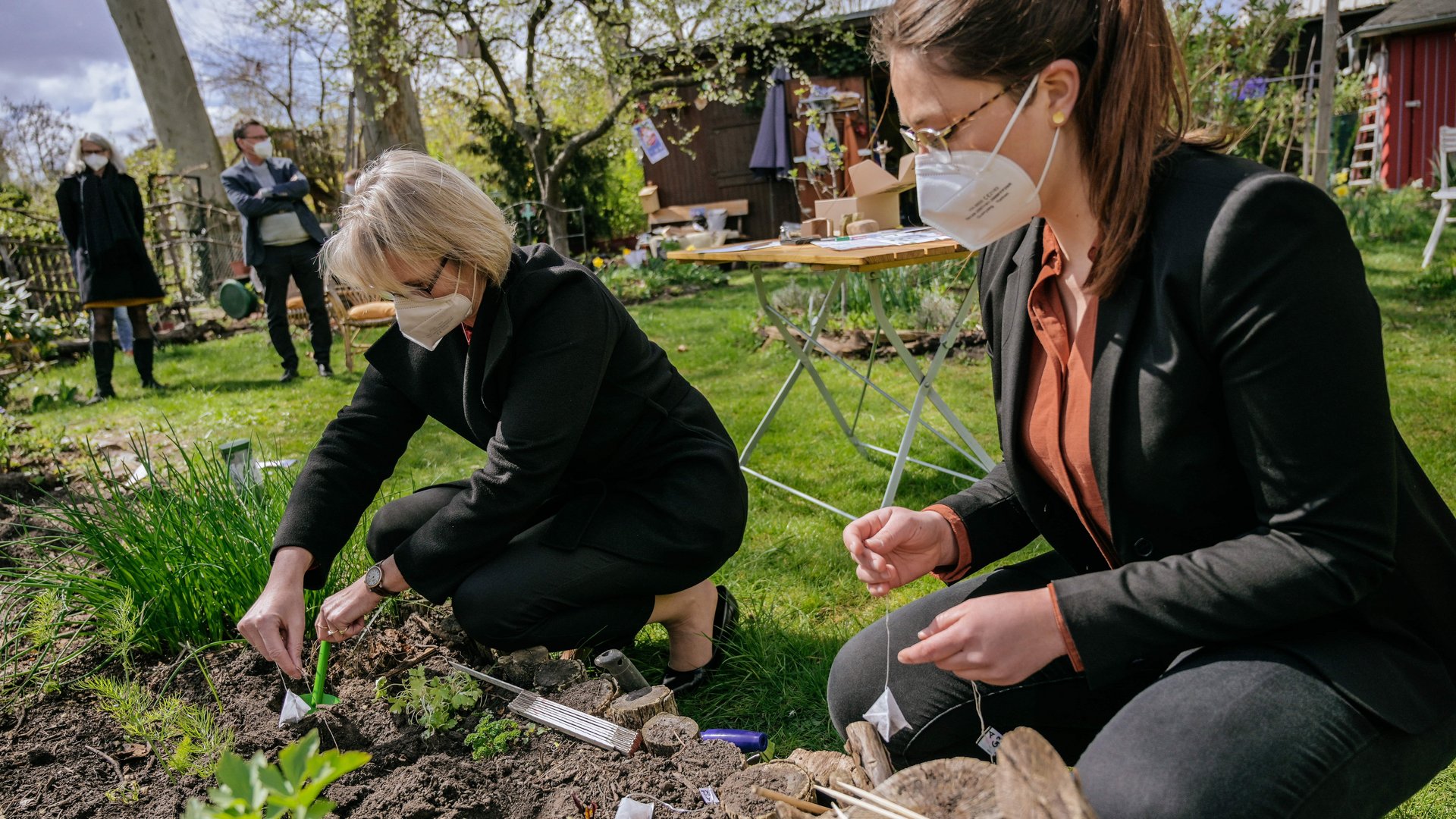 Anja Karliczek und Luise Ohmann vergraben einen Teebeutel