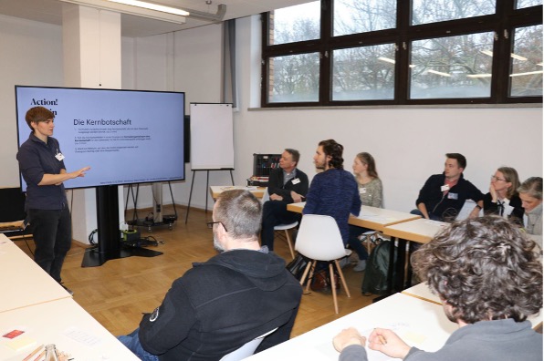 Eine Gruppe an Menschen hört Dr. Annika Kreikenbohm zu. 