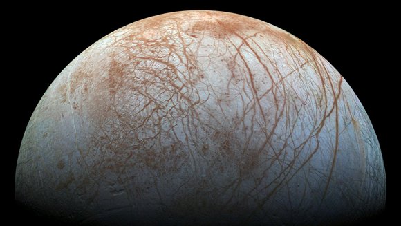 Eismond Europa mit heller Oberfläche, die von rostroten Rissen durchzogen ist; schwarzer Hintergrund.