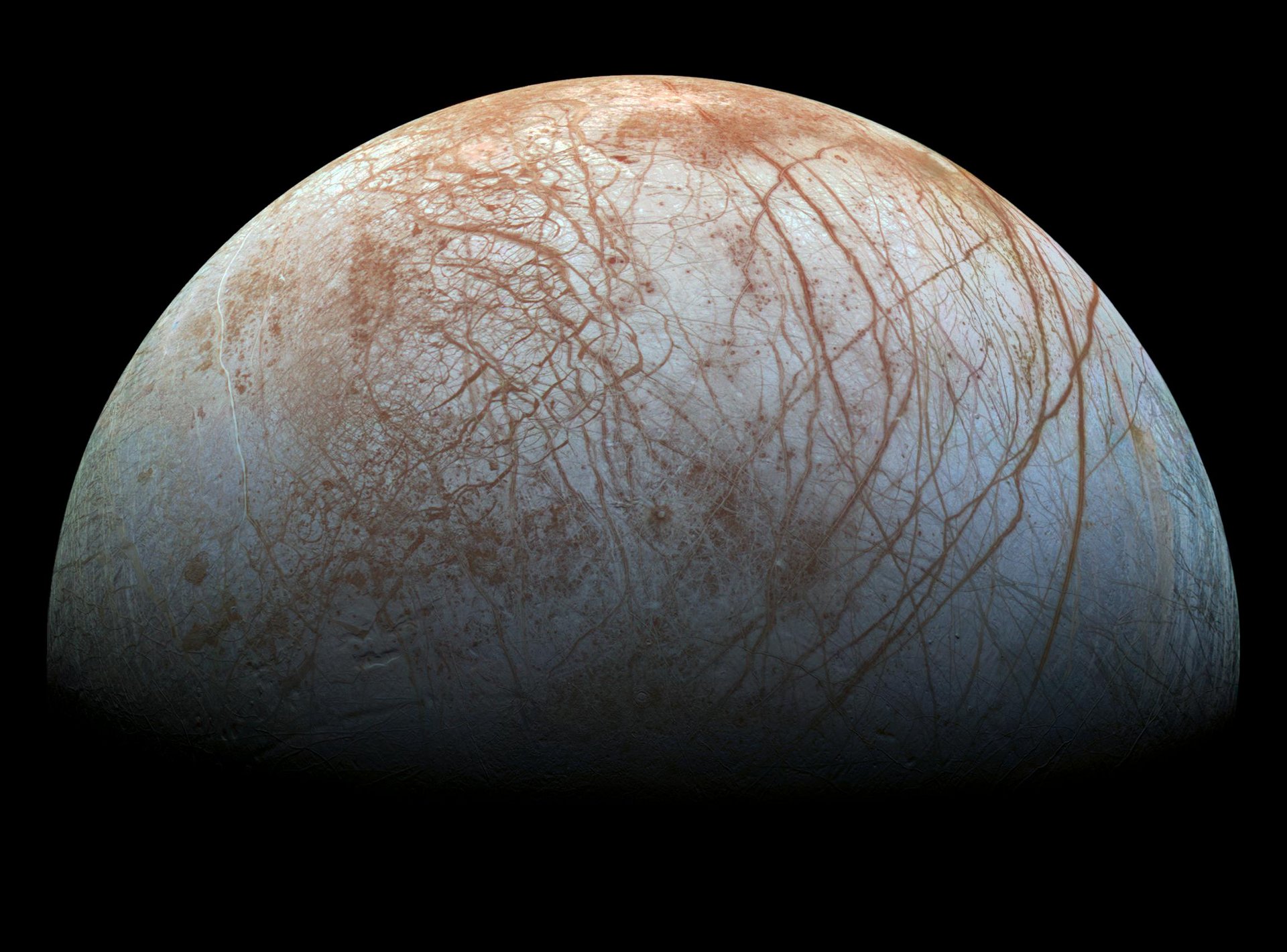 Eismond Europa mit heller Oberfläche, die von rostroten Rissen durchzogen ist; schwarzer Hintergrund.