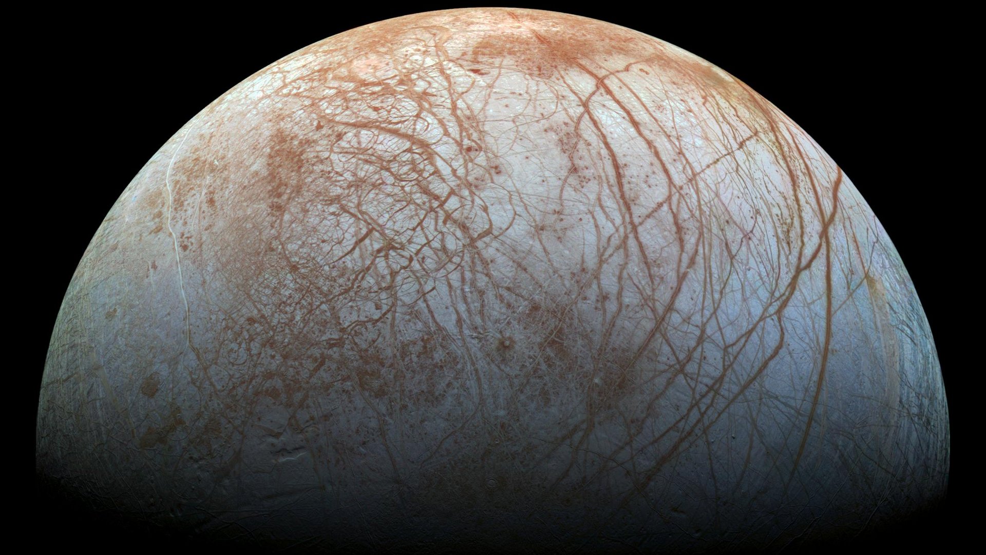 Eismond Europa mit heller Oberfläche, die von rostroten Rissen durchzogen ist; schwarzer Hintergrund.