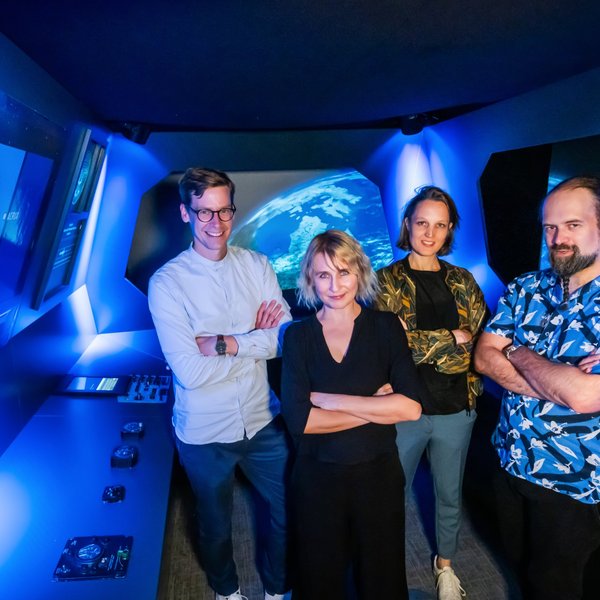 Ein Teil der Mitwirkenden in einem blau erleuchteten Raum