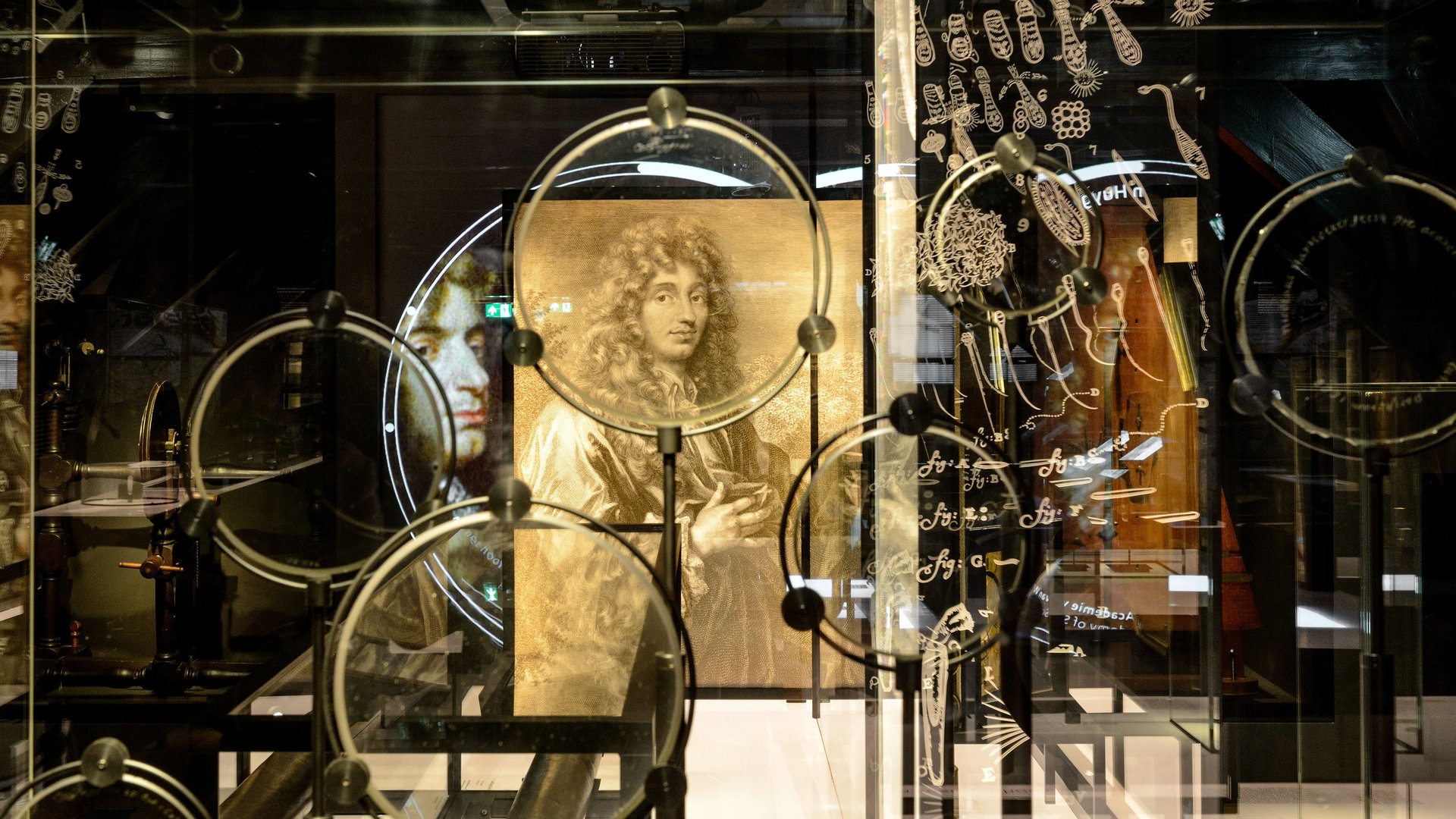 Eine Sammlung von Linsen von Christiaan Huygens mit seinem Porträt im Hintergrund.