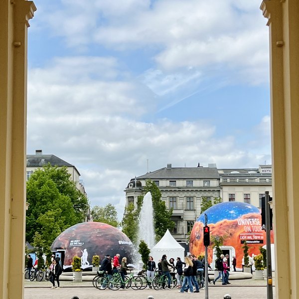 Foto vom Planetariumszelt in der Ferne, die fotografierende Person steht unter einem Torbogen
