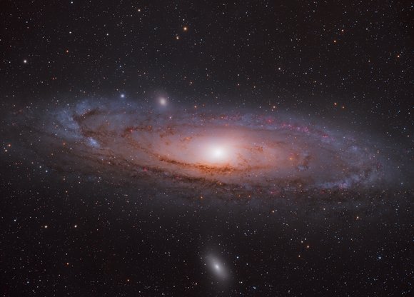 Eine strudelartige rosa Galaxie im Universum umgeben von Sternen.