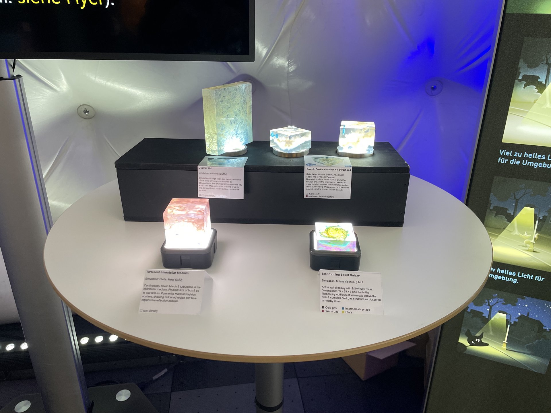 Kleine Ausstellungsmodelle verschiedener Galaxien auf einem Tisch