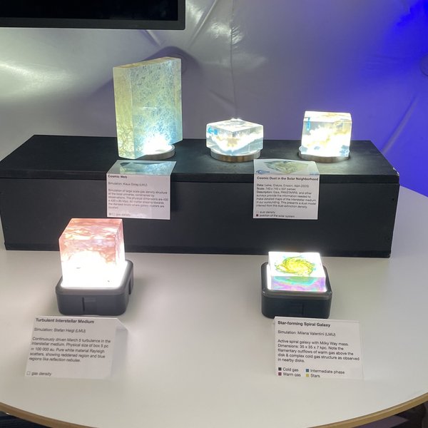 Kleine Ausstellungsmodelle verschiedener Galaxien auf einem Tisch