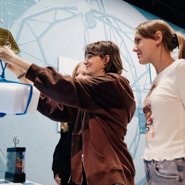 Drei Kinder schauen ein Ausstellungsstück an. 